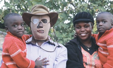 man wearing a mask next to a woman both holding children